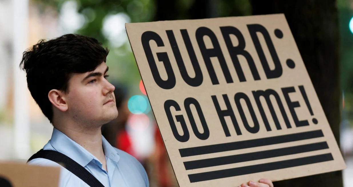 A protestor holds a sign at a rally at Mark O. Hatfield Federal Courthouse, as protestors anticipate a ruling by Federal District Court Judge Karin Immergut regarding President Donald Trump's plan to deploy National Guard members in Portland, in Portland, Oregon, U.S., October 3, 2025. REUTERS/John Rudoff/John Rudoff