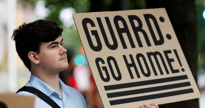 A protestor holds a sign at a rally at Mark O. Hatfield Federal Courthouse, as protestors anticipate a ruling by Federal District Court Judge Karin Immergut regarding President Donald Trump's plan to deploy National Guard members in Portland, in Portland, Oregon, U.S., October 3, 2025. REUTERS/John Rudoff/John Rudoff