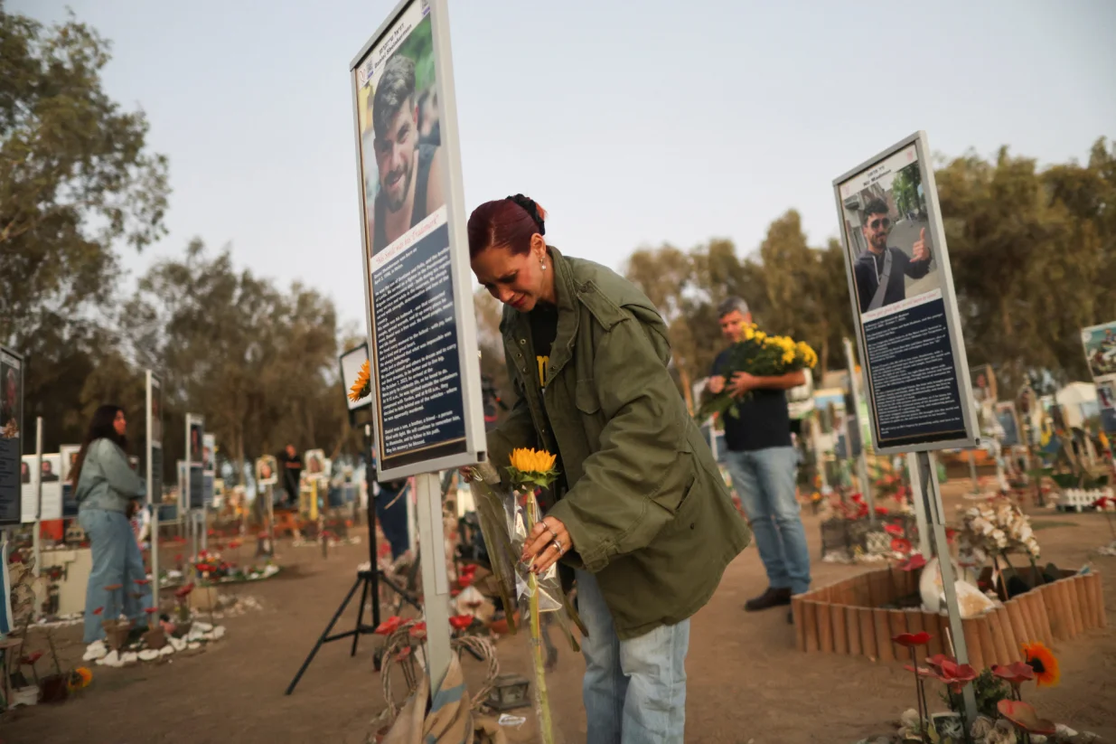 A woman places a flower as people grieve at the site of the Nova festival where partygoers were killed and kidnapped, on the two-year anniversary of the deadly October 7, 2023 attack on Israel by Hamas from Gaza, in Reim, southern Israel, October 7, 2025. REUTERS/Itay Cohen/Itay Cohen