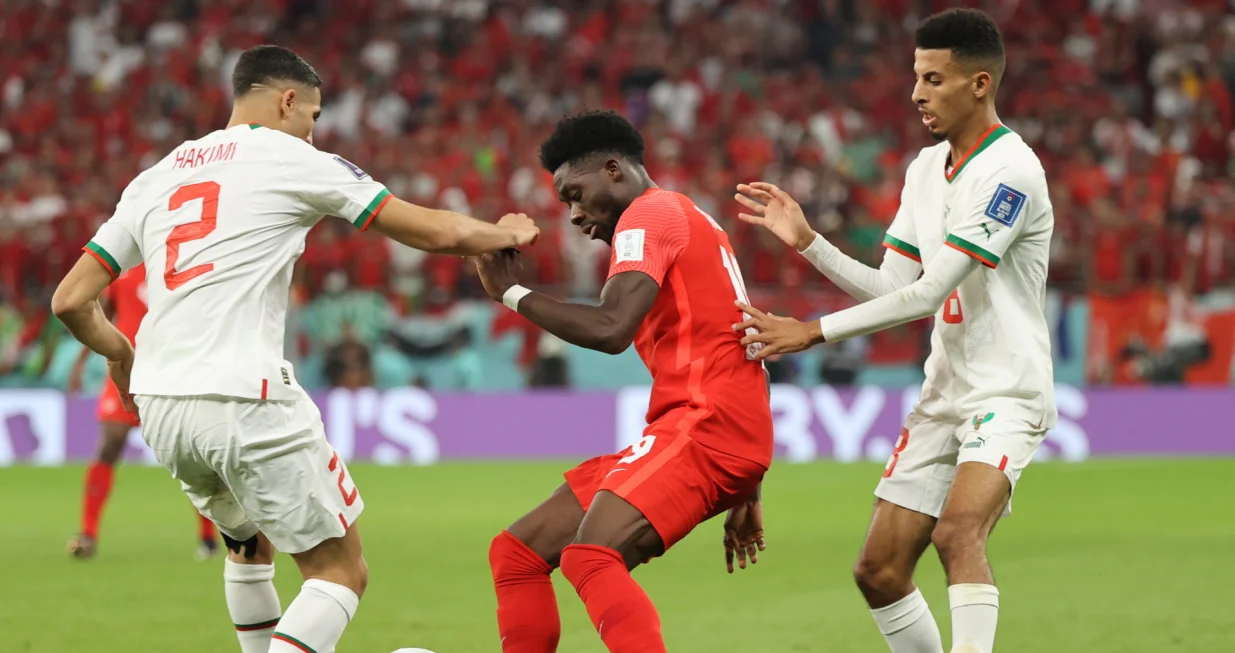 epa10341915 Alphonso Davies (C) of Canada in action against Achraf Hakimi (L) of Morocco during the FIFA World Cup 2022 group F soccer match between Canada and Morocco at Al Thumama Stadium in Doha, Qatar, 01 December 2022. EPA/Mohamed Messara/Foto: Mohamed Messara