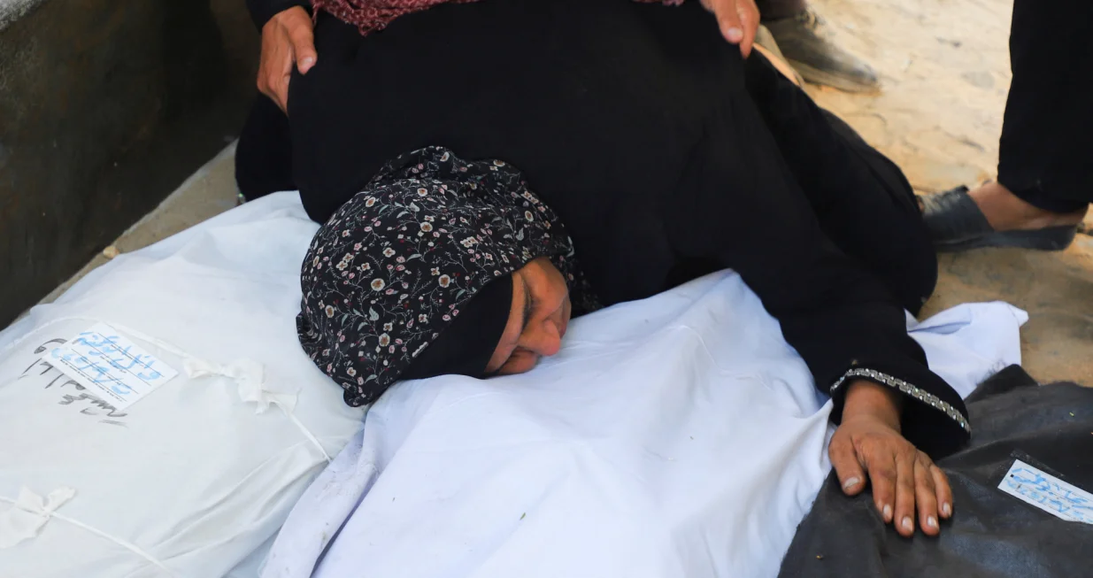 A relative embraces body bags, during the funeral for members of the Abu Amsha family, who were killed in an Israeli strike on a house on Saturday amid their military operation, according to medics, at Al-Shifa Hospital in Gaza City, September 21, 2025. REUTERS/Ebrahim Hajjaj/Ebrahim Hajjaj