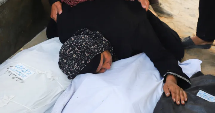A relative embraces body bags, during the funeral for members of the Abu Amsha family, who were killed in an Israeli strike on a house on Saturday amid their military operation, according to medics, at Al-Shifa Hospital in Gaza City, September 21, 2025. REUTERS/Ebrahim Hajjaj/Ebrahim Hajjaj