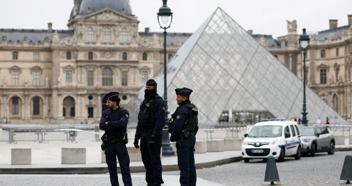 Police officers stand near the pyramid of the Louvre museum after reports of a robbery, in Paris, France, October 19, 2025. REUTERS/Gonzalo Fuentes  TPX IMAGES OF THE DAY/Gonzalo Fuentes