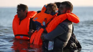 Migrants wade through the sea in an attempt to board an inflatable dinghy, leaving the beach of Petit-Fort-Philippe in northern France to cross the English Channel to reach Britain, in Gravelines, near Calais, France, September 27, 2025. REUTERS/Abdul Saboor/Abdul Saboor