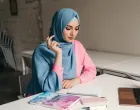 young pretty modern muslim woman in hijab working on laptop in office room, education online, remote work freelancer, making notes thinking, hidžab, posao, žena/Freepik