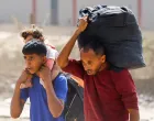 Palestinians, who were displaced to the southern part of Gaza at Israel's order during the war, carry their belongings and a child, while they return to the north, amid a ceasefire between Israel and Hamas in Gaza, in the central Gaza Strip, October 12, 2025. REUTERS/Mahmoud Issa/Mahmoud Issa