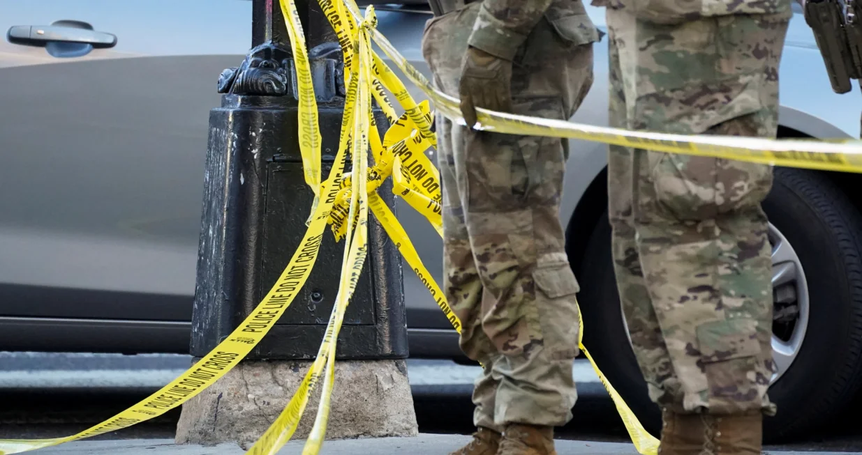 National Guard members stand together behind yellow tape, after two National Guard members were shot near the White House in Washington, D.C., U.S., November 26, 2025. REUTERS/Nathan Howard/Nathan Howard