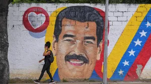 A woman walks past a mural of Venezuela's President Nicolas Maduro amid rising tensions between the administration of U.S. President Donald Trump and the government of Venezuela's President Nicolas Maduro, in Caracas, Venezuela, November 24, 2025. REUTERS/Gaby Oraa/Gaby Oraa