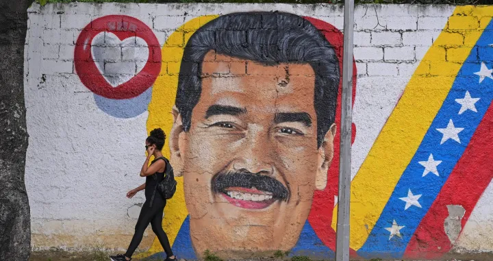 A woman walks past a mural of Venezuela's President Nicolas Maduro amid rising tensions between the administration of U.S. President Donald Trump and the government of Venezuela's President Nicolas Maduro, in Caracas, Venezuela, November 24, 2025. REUTERS/Gaby Oraa/Gaby Oraa
