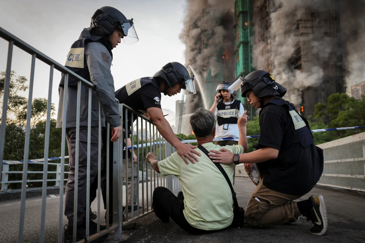 Police officers calm Wong, a 71-year-old man who claims his wife is trapped inside Wang Fuk Court housing complex during a major fire, in Tai Po, Hong Kong, China, November 26, 2025. REUTERS/Tyrone Siu   SEARCH "HONG KONG FIRE PICTURE" FOR THIS STORY. SEARCH "WIDER IMAGE" FOR ALL STORIES.  TPX IMAGES OF THE DAY/Tyrone Siu