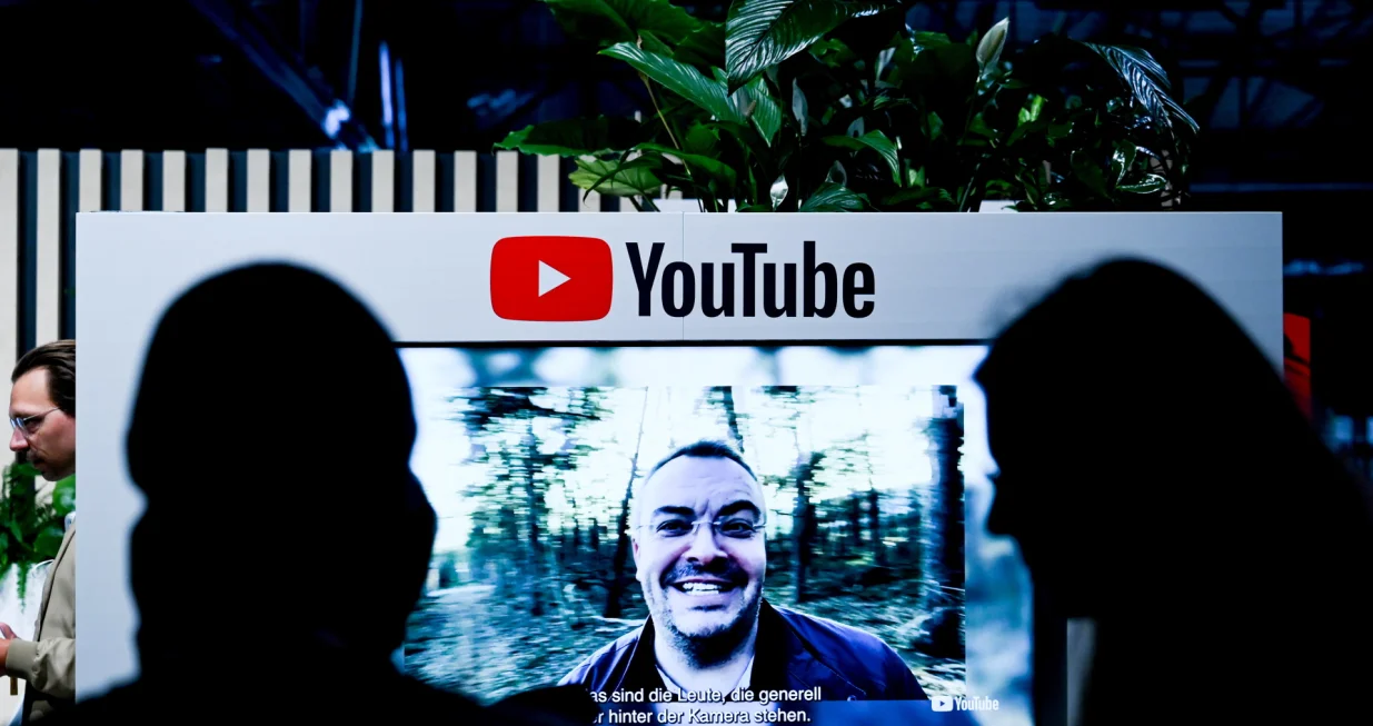 epa10004040 Visitors next to a screen with YouTube logo at the 're:publica 22' digital conference in Berlin, Germany, 09 June 2022. The 're:publica' is one of the largest conferences about digital culture, blogs, social media and information society in the world. It takes place annually in Berlin and runs from 08 to 10 June. EPA/FILIP SINGER/Filip Singer