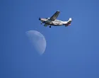 epa09351010 A Cessna 208B Grand Caravan Aircraft G-EELS fly's past the moon over the Royal St George's golf course during the 3rd round of The Open 2021 golf championship at in Sandwich, Kent, Britain, 17 July 2021. EPA/NEIL HALL/Neil Hall