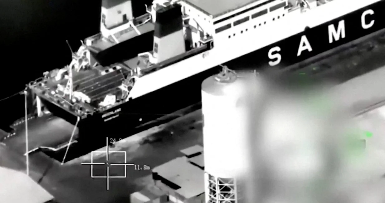 A screenshot from footage released by the Saudi-led Coalition shows what is says is the arrival of the "Greeland" ship from Al Fujairah port to Al Mukalla Port, carrying what it described as foreign military support to UAE-backed southern separatists, in Yemen's southern port of Mukalla, in this screengrab from a handout video obtained by Reuters on December 30, 2025. Saudi-led Coalition/Handout via REUTERS THIS IMAGE HAS BEEN SUPPLIED BY A THIRD PARTY. TEXT OVERLAY AND BLURRING FROM SOURCE. VERIFICATION LINES: Storage tanks, vehicles and the wall match with satellite images and corroborating footages showing the fire. Date not verified by Reuters./Saudi-led Coalition