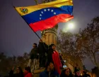 A woman waves a large Venezuelan flag as Venezuelans and others celebrate in Barcelona following Saturday's U.S. strikes on Venezuela, during which President Nicolas Maduro and his wife, Cilia Flores, were captured, Spain, January 4, 2026. REUTERS/Bruna Casas  TPX IMAGES OF THE DAY/Bruna Casas