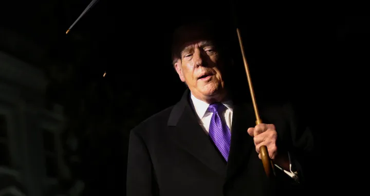 U.S. President Donald Trump holds an umbrella as he speaks to members of the media while departing the White House en route to Florida in Washington, D.C., U.S., January 9, 2026. REUTERS/Kevin Lamarque/Kevin Lamarque