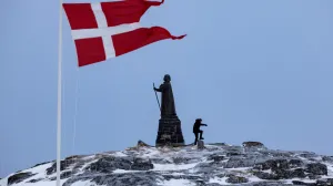 FILE PHOTO: A man walks as Danish flag flutters next to Hans Egede Statue ahead of a March 11 general election in Nuuk, Greenland, March 9, 2025. REUTERS/Marko Djurica/File Photo/Marko Djurica