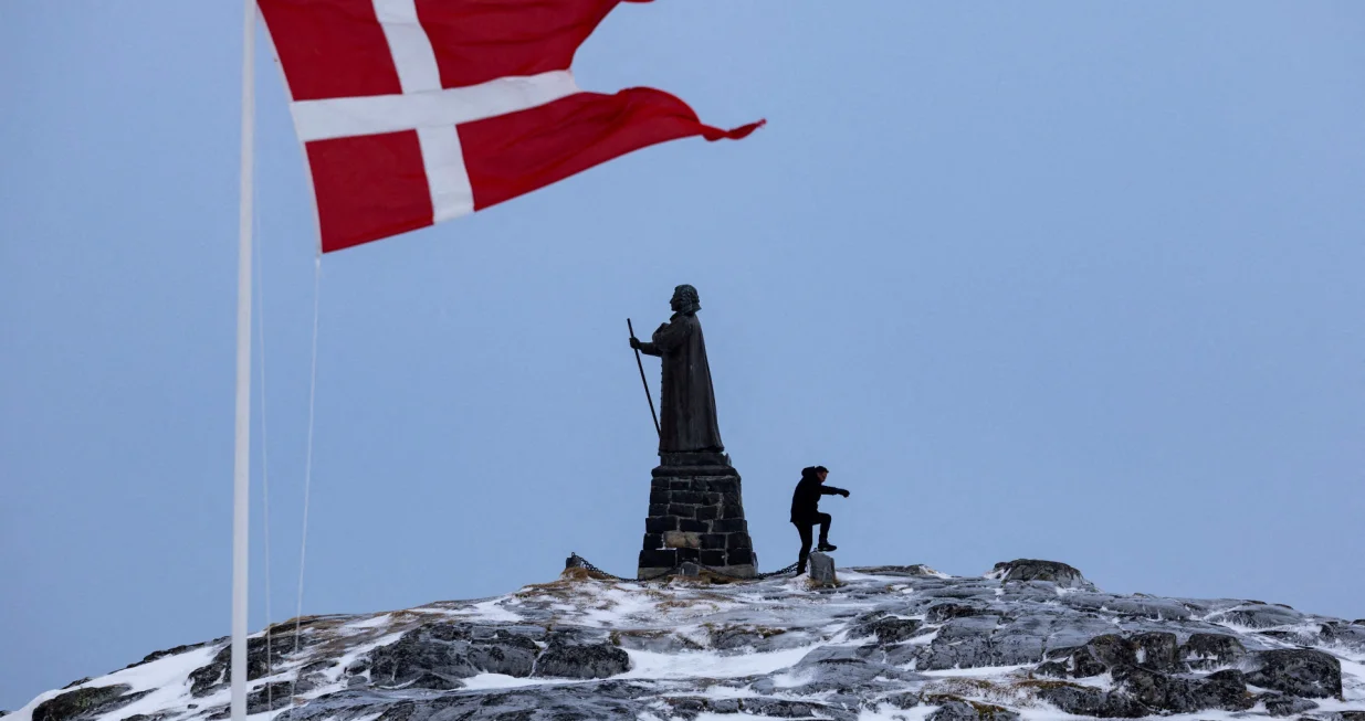 FILE PHOTO: A man walks as Danish flag flutters next to Hans Egede Statue ahead of a March 11 general election in Nuuk, Greenland, March 9, 2025. REUTERS/Marko Djurica/File Photo/Marko Djurica