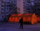 A resident walks past a tent of a government-run humanitarian aid point, where residents can warm up, charge their devices, get hot drinks and psychological support, installed next to apartment buildings during a power blackout after critical civil infrastructure was hit by overnight Russian missile and drone strikes, amid Russia's attack on Ukraine, in Kyiv, Ukraine, January 20, 2026. REUTERS/Valentyn Ogirenko/Valentyn Ogirenko