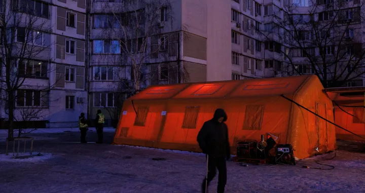 A resident walks past a tent of a government-run humanitarian aid point, where residents can warm up, charge their devices, get hot drinks and psychological support, installed next to apartment buildings during a power blackout after critical civil infrastructure was hit by overnight Russian missile and drone strikes, amid Russia's attack on Ukraine, in Kyiv, Ukraine, January 20, 2026. REUTERS/Valentyn Ogirenko/Valentyn Ogirenko