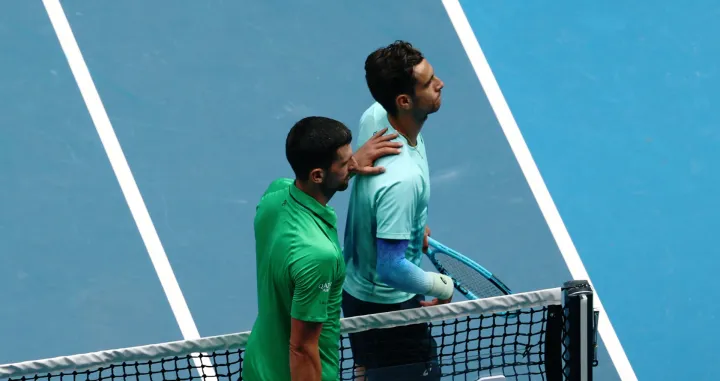 Tennis - Australian Open - Melbourne Park, Melbourne, Australia - January 28, 2026 Italy's Lorenzo Musetti with Serbia's Novak Djokovic after retiring from his quarter final match REUTERS/Tingshu Wang/Foto: Tingshu Wang