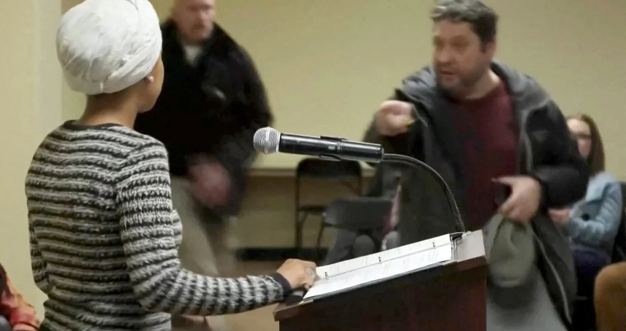 A man shouts at U.S. Representative Ilhan Omar (D-MN) after spraying an unidentified liquid in her direction, during a town hall meeting days after a man identified as Alex Pretti was fatally shot by federal immigration agents trying to detain him, in Minneapolis, Minnesota, U.S., January 27, 2026 in a still image from video. REUTERS/Maria Alejandra Cardona  TPX IMAGES OF THE DAY/Maria Alejandra Cardona