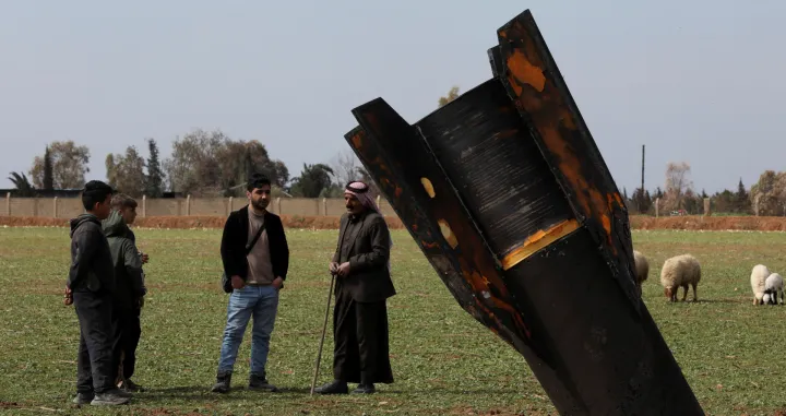 People stand next to a missile after it fell near Qamishli International Airport, amid the U.S.-Israeli conflict with Iran, in Qamishli, Syria, March 4, 2026. REUTERS/Orhan Qereman REFILE &ndash; REMOVING ATTRIBUTION OF THE MISSILE/Orhan Qereman