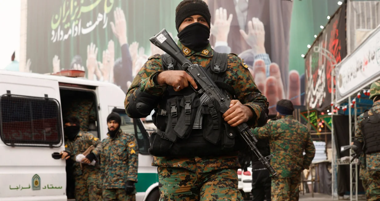 Members of the police stand guard on a street, with a large billboard featuring Iran's late Supreme Leader Ayatollah Ali Khamenei in the background, amid the U.S.-Israeli conflict with Iran, in Tehran, Iran, March 12, 2026. REUTERS/Alaa Al-Marjani/Alaa Al-marjani