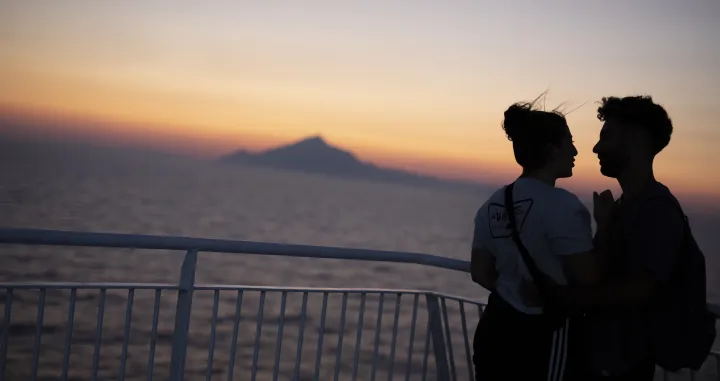 epa08615247 A couple enjoys the sunset on the deck of the ferry boat 'Nissos Mykonos', while sailing in the Aegean sea, Greece, 20 August 2020. EPA/DIMITRIS TOSIDIS/Dimitris Tosidis